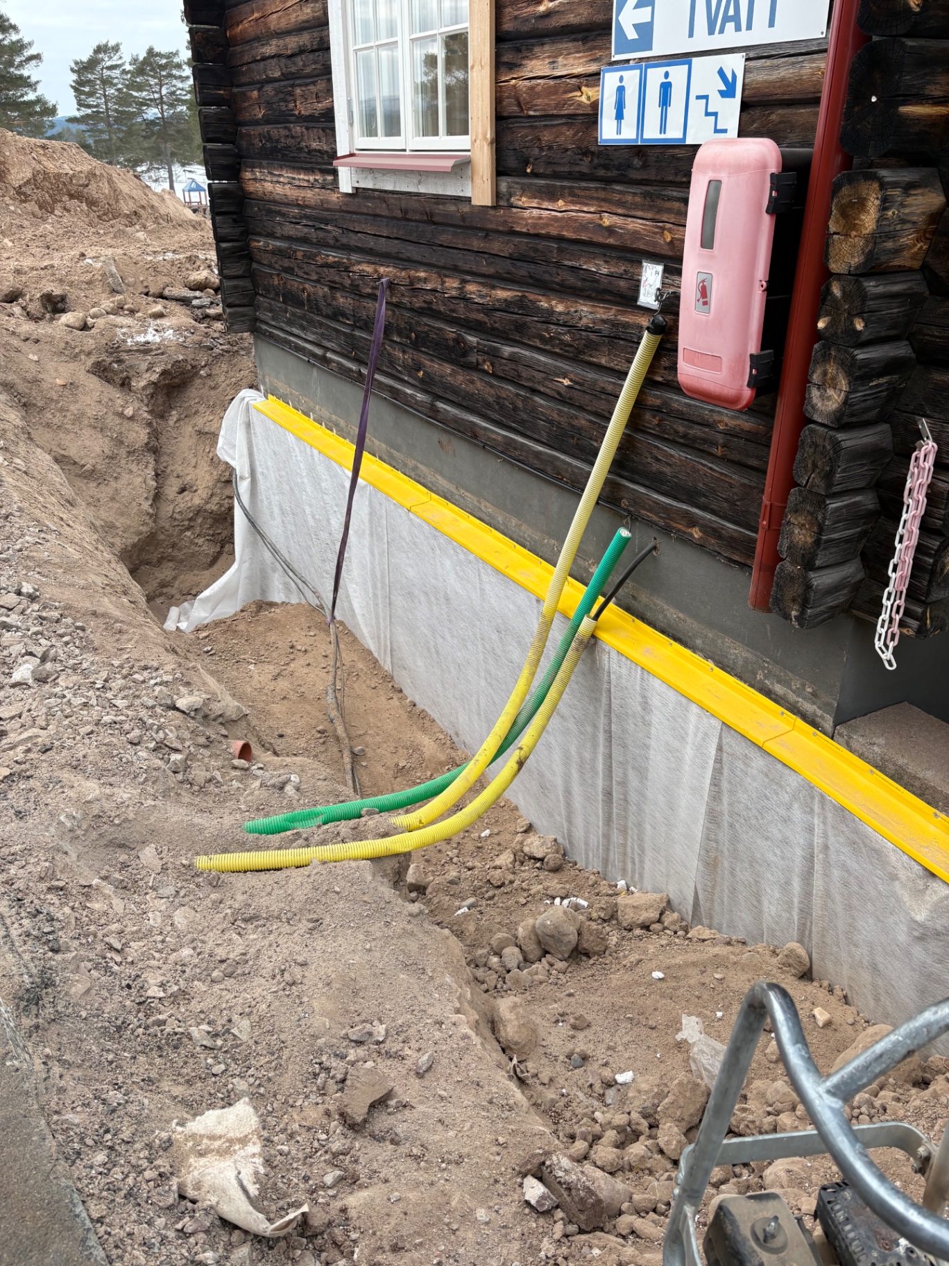 Vit fiberduk och gul täcklist monterade på ett timmerhus sockel med skyddsrör längs fasaden